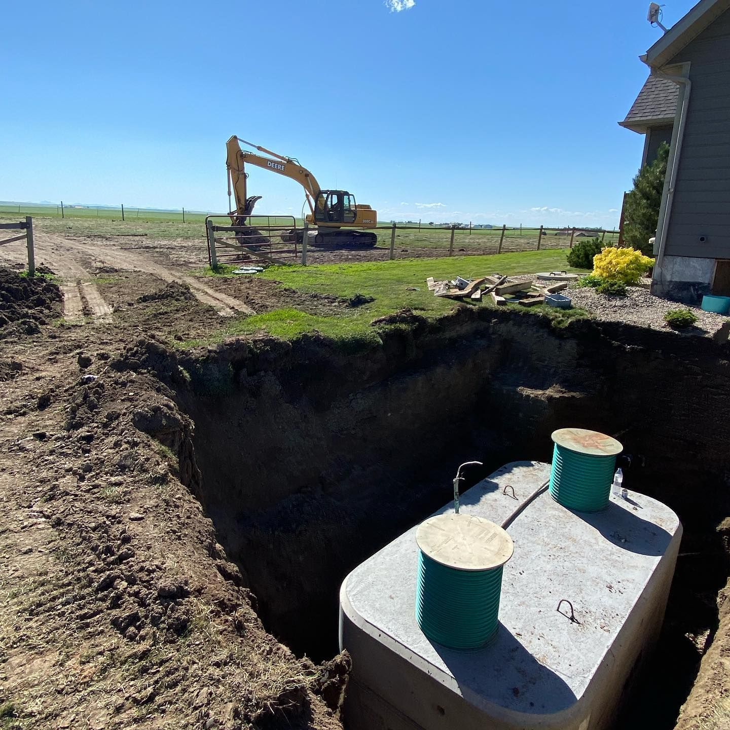 A septic tank is being installed in the dirt in front of a house