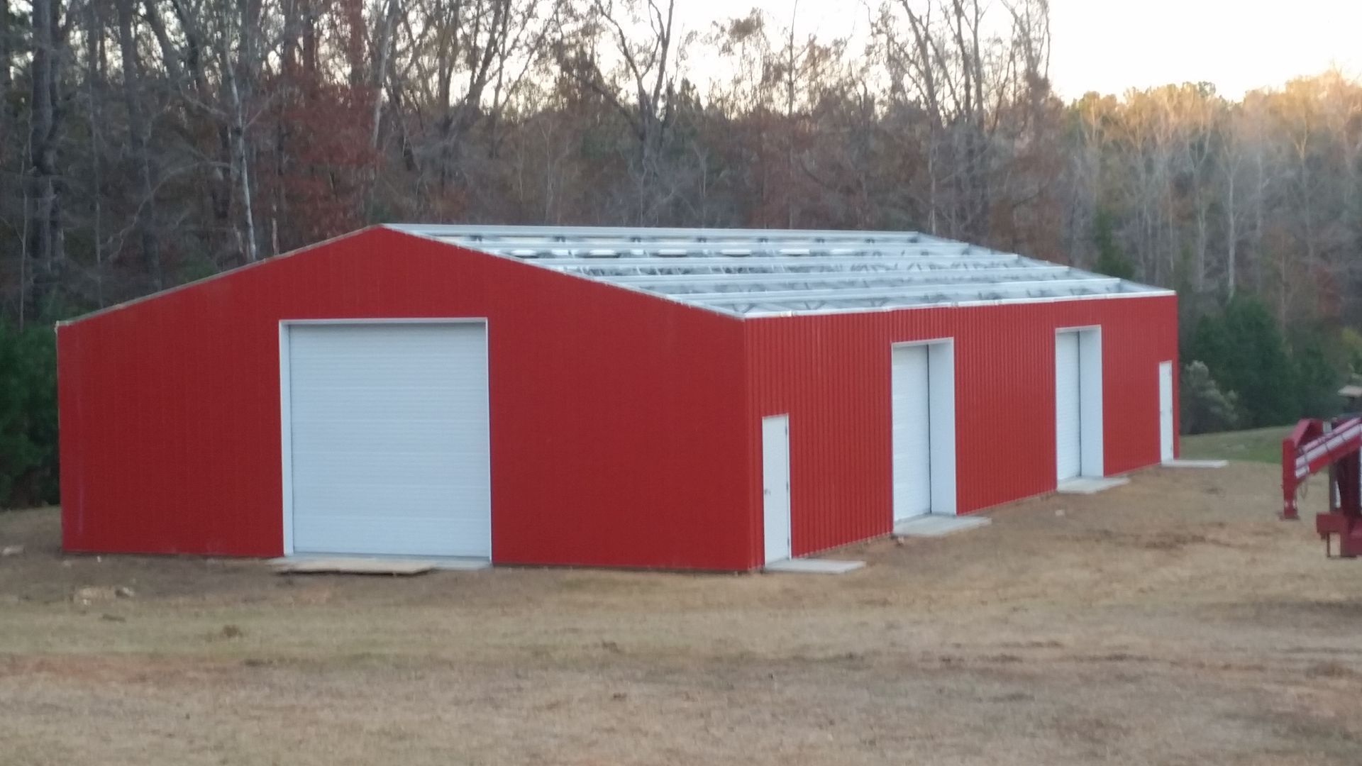 A red building with white doors is being built in a field