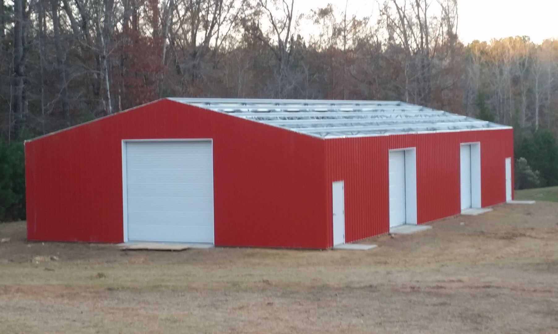 A red building with white doors is being built in a field