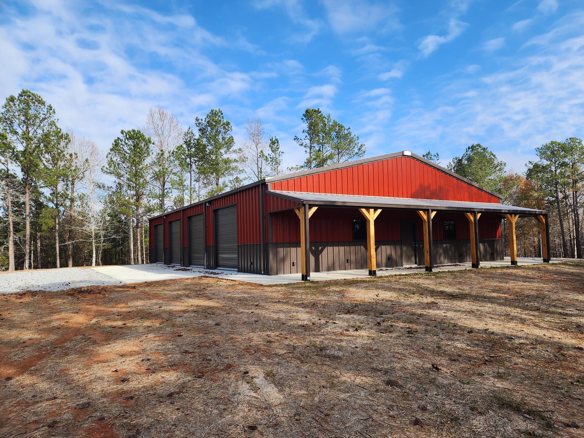 A large red barn with a porch in the middle of a field.