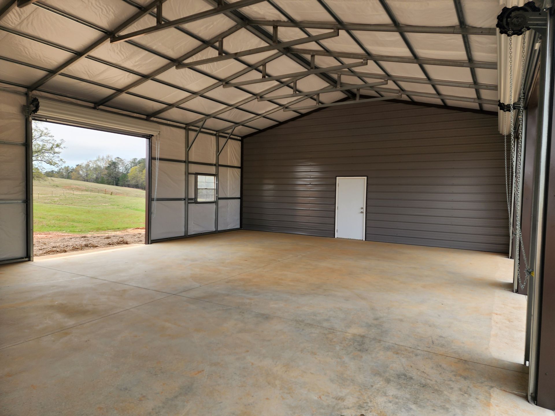 A large empty building with a large garage door open.