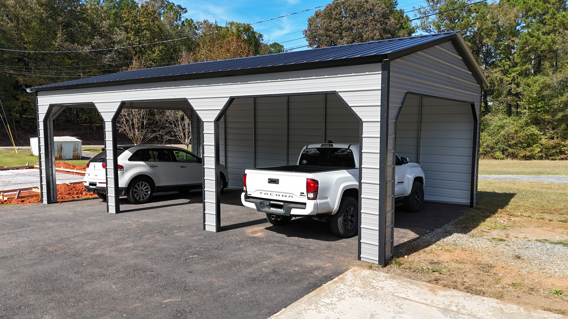 A gray carport shelters a white SUV and pickup truck, with a dark blue roof.