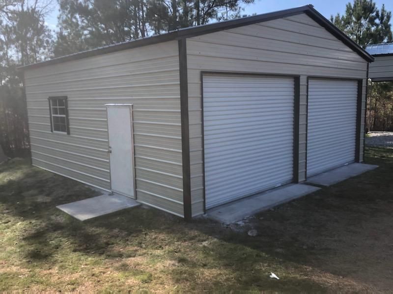 A metal garage with two garage doors and a door.