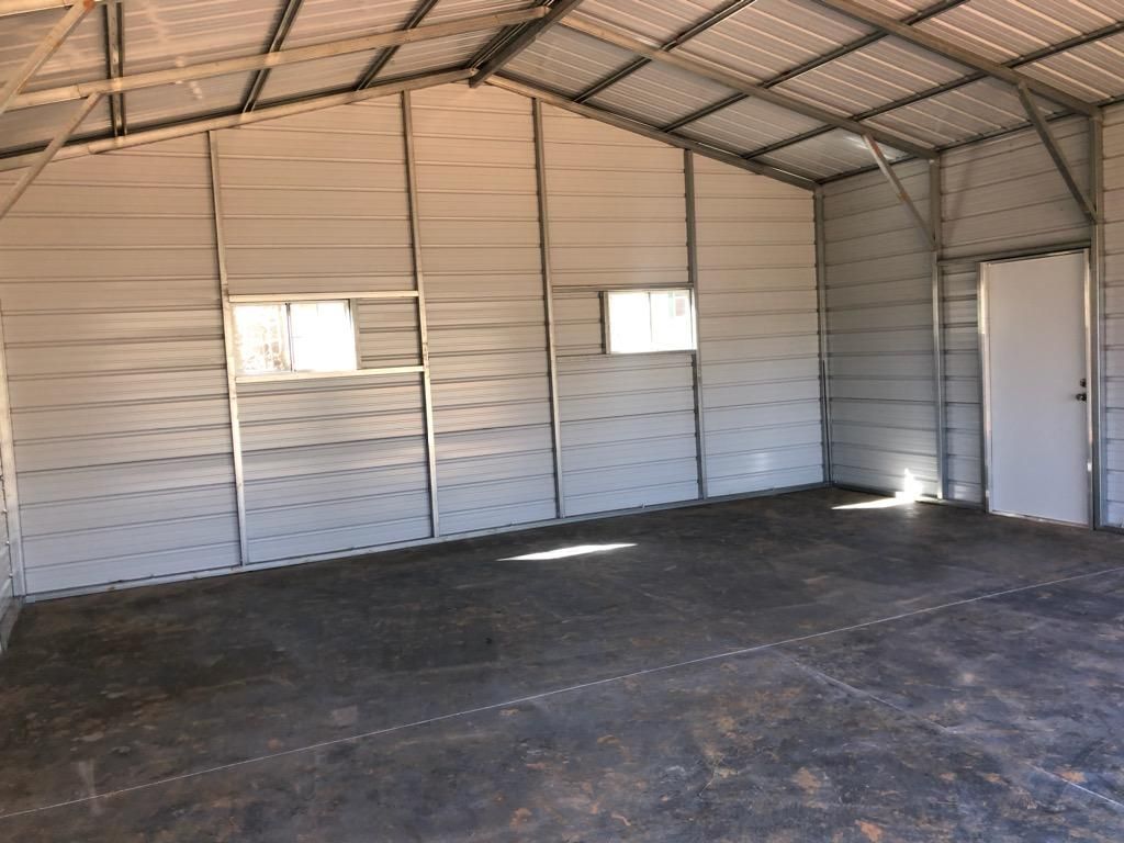An empty garage with a concrete floor and a metal roof.