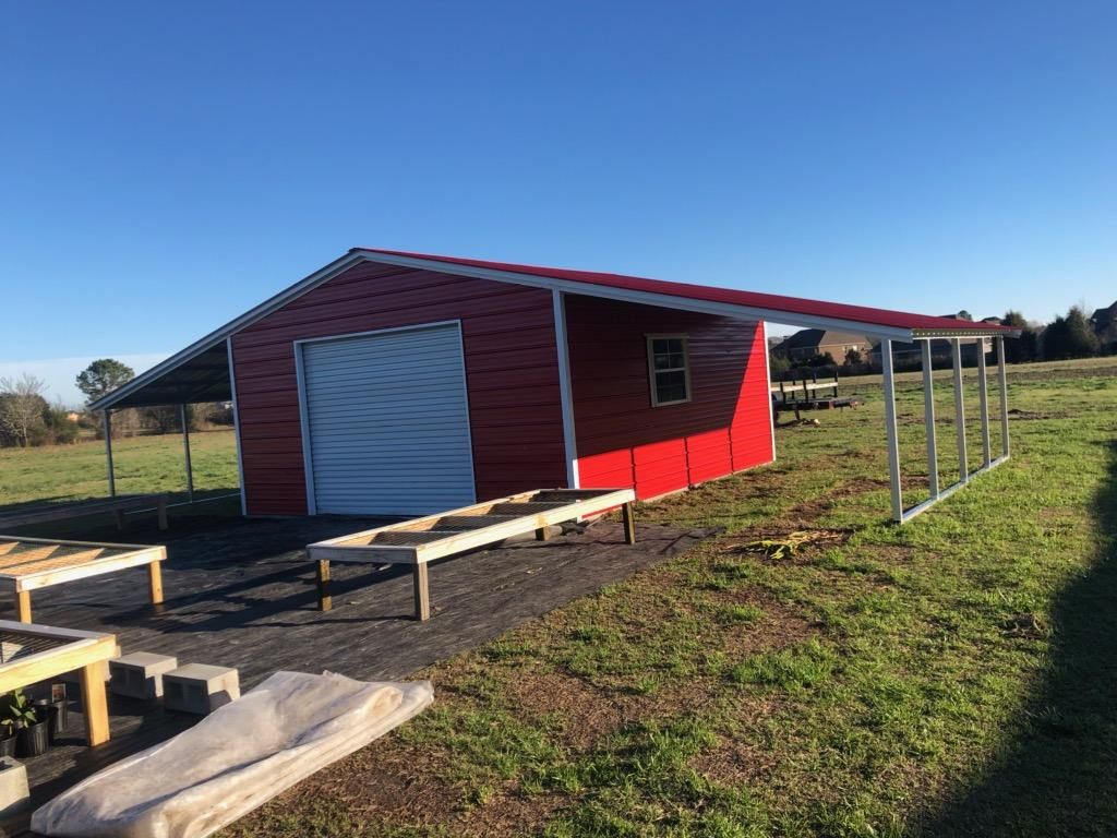 A red barn is sitting in the middle of a grassy field.
