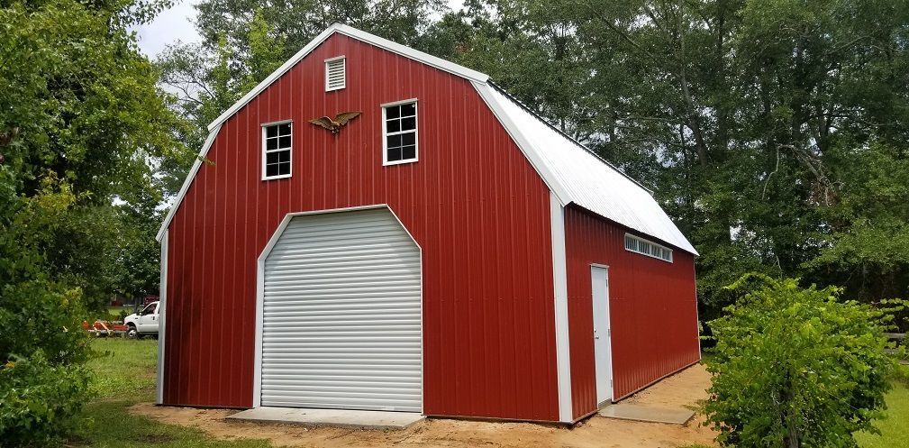 A red barn with a white roof is sitting in the middle of a field.