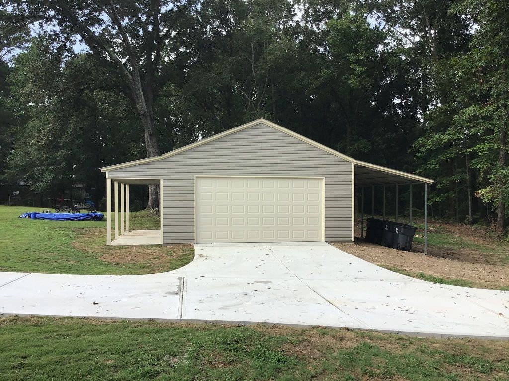 A garage with a carport attached to it and a driveway leading to it.