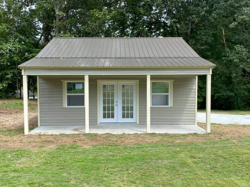 A small house with a porch and a metal roof