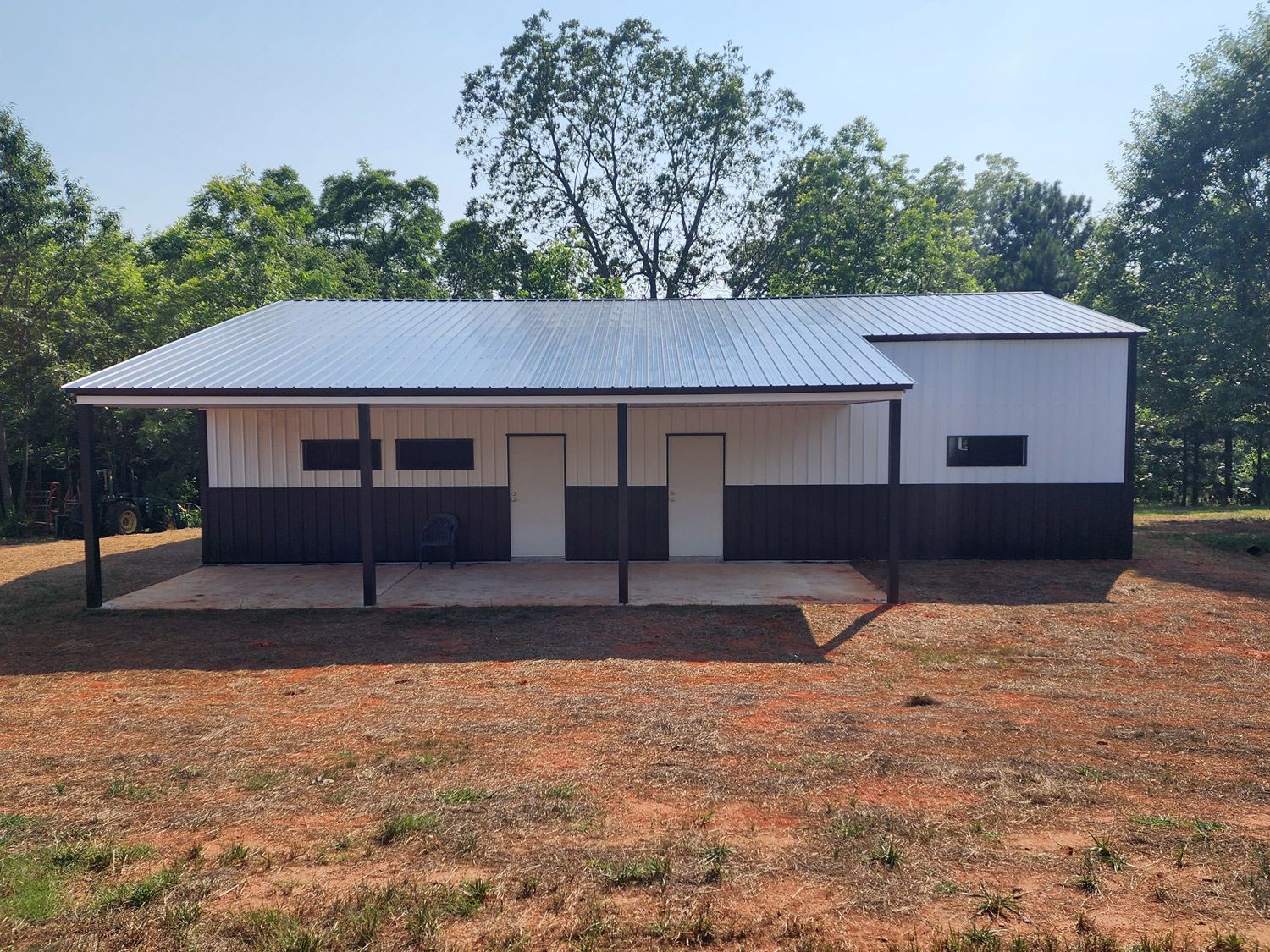 A white and black house with a metal roof is sitting in the middle of a field.