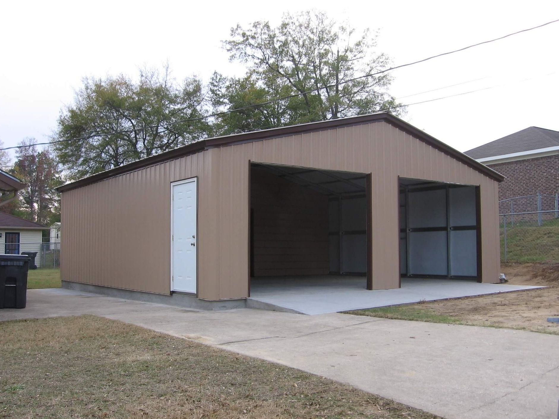 A garage with two doors and a trash can in front of it