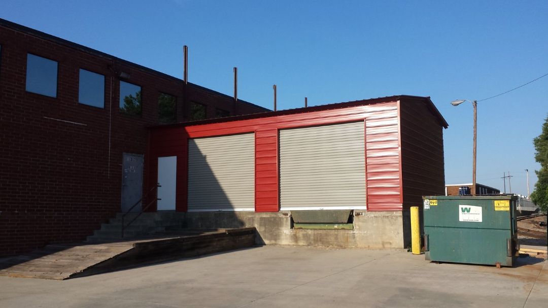 A brick building with a green dumpster in front of it