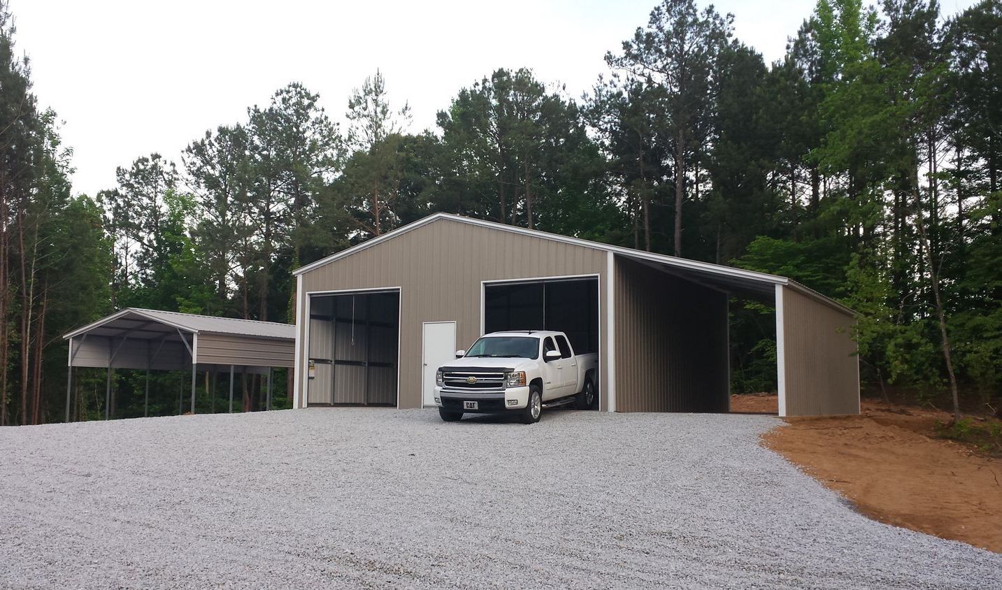 A white truck is parked in front of a metal building