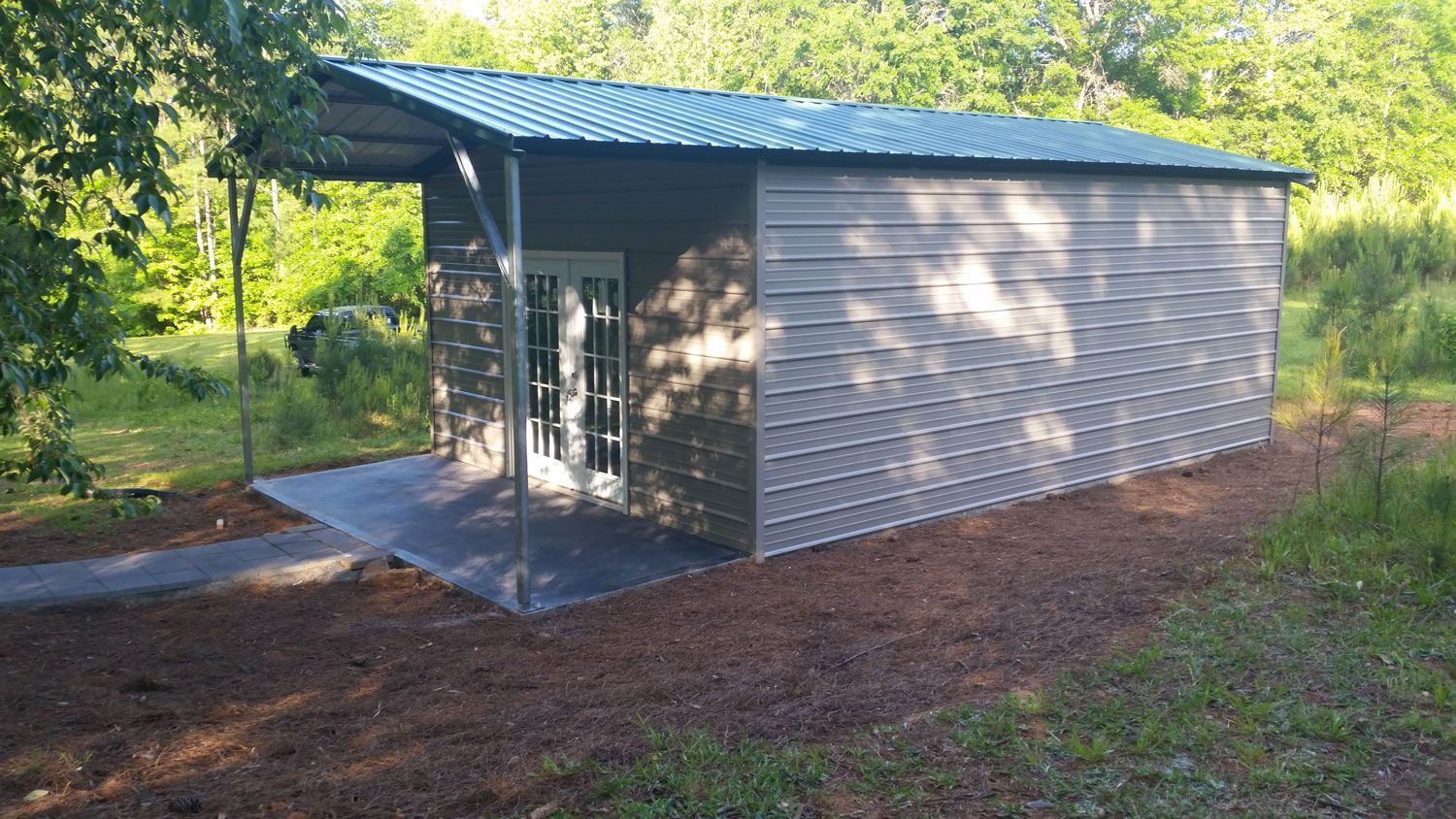 A small metal building with a roof and a door is sitting in the middle of a field.