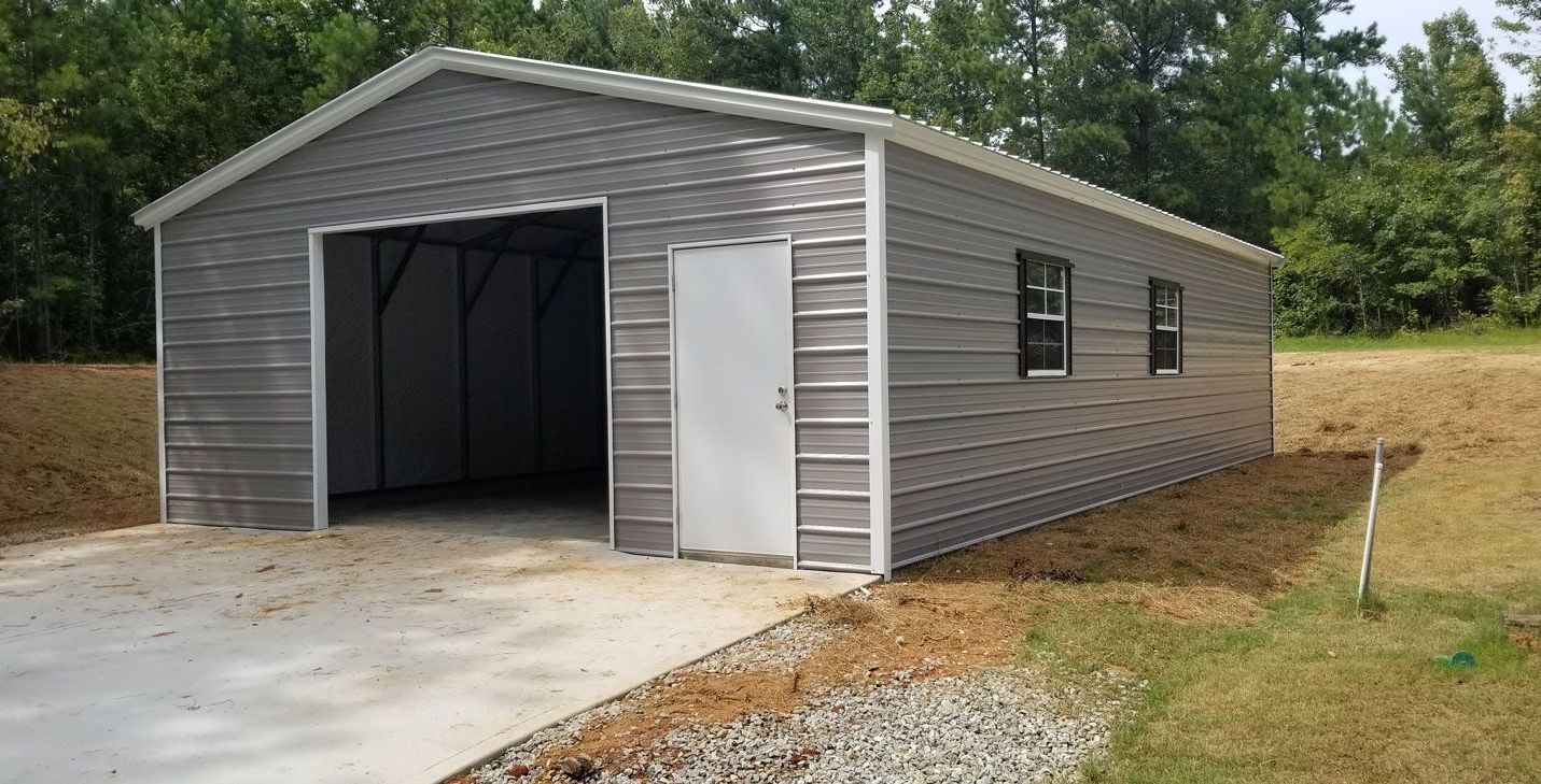 A large metal garage with a driveway in front of it.