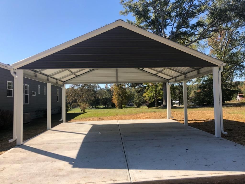A carport is sitting on top of a concrete driveway next to a house.
