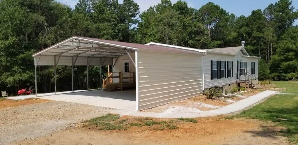 A white house with a large metal garage in front of it.
