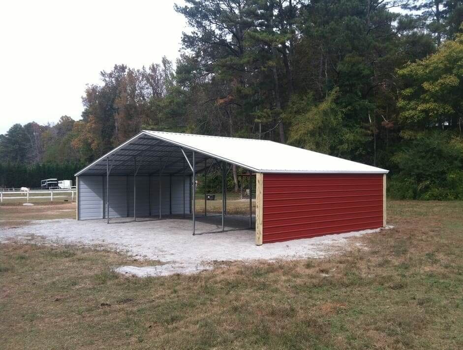 A red barn with a white roof is in the middle of a field