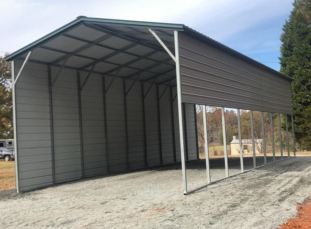 A large metal building is sitting on top of a gravel road.