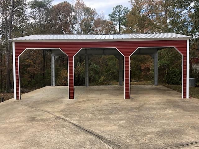 A red carport is sitting on top of a concrete driveway.