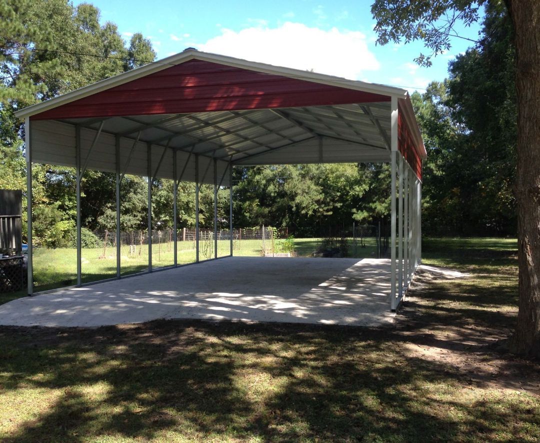 A red and white carport is sitting in the middle of a grassy field.