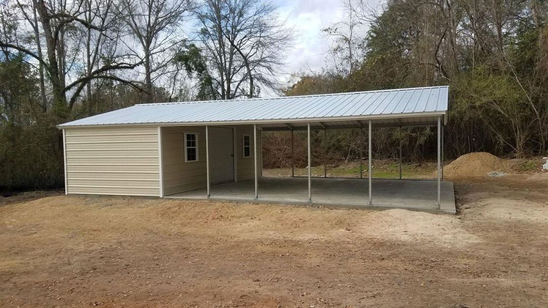 A metal garage with a porch and a concrete floor is sitting in the middle of a dirt field.