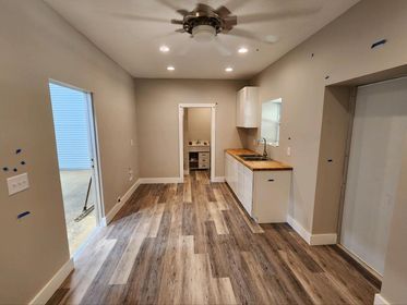 A kitchen with wooden floors and a ceiling fan.