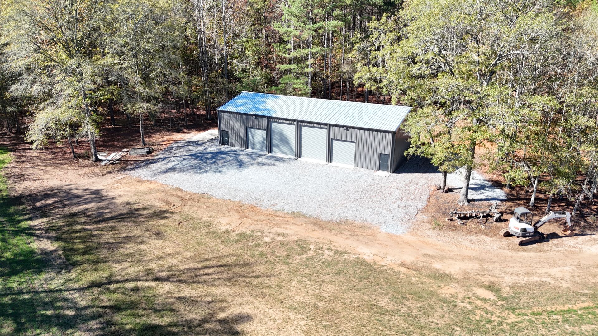 An aerial view of a garage in the middle of a field surrounded by trees.