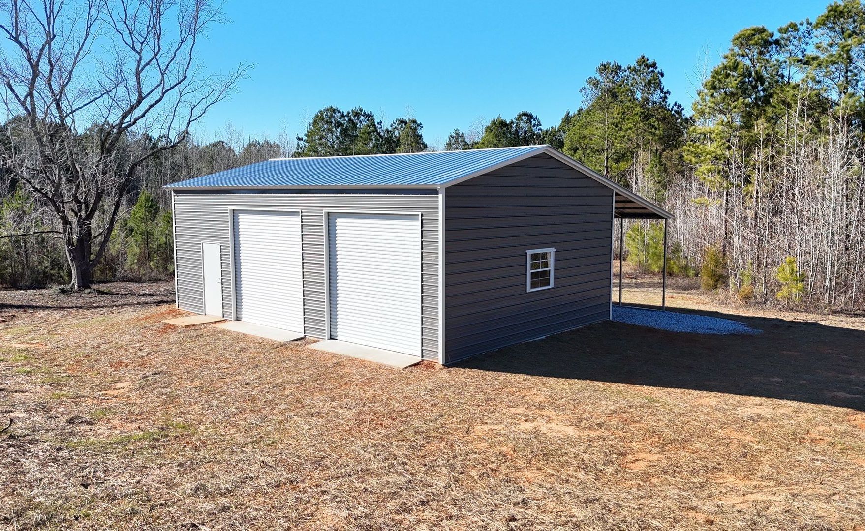 A large metal garage is sitting in the middle of a field.
