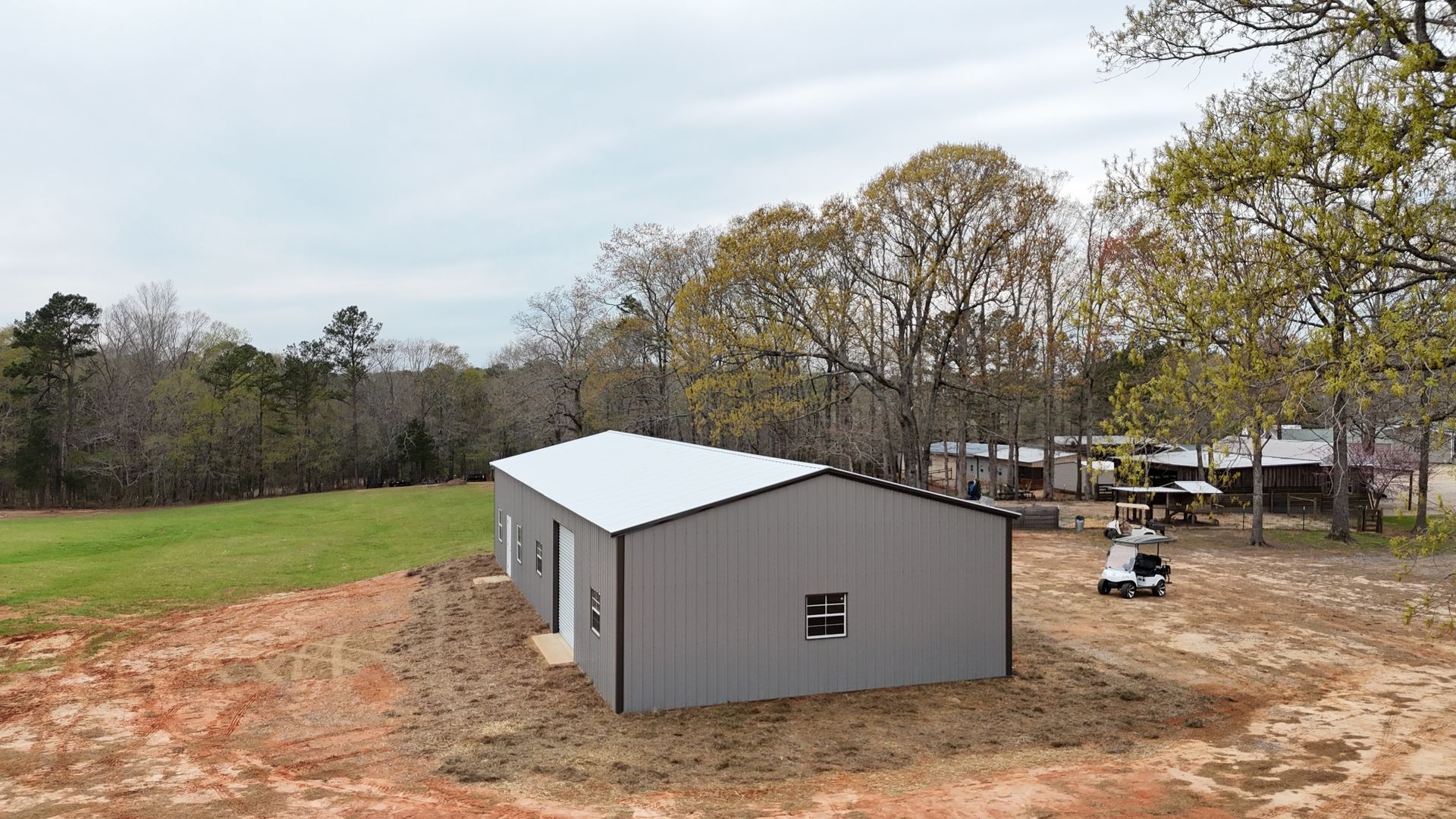 A large metal building is sitting in the middle of a dirt field.