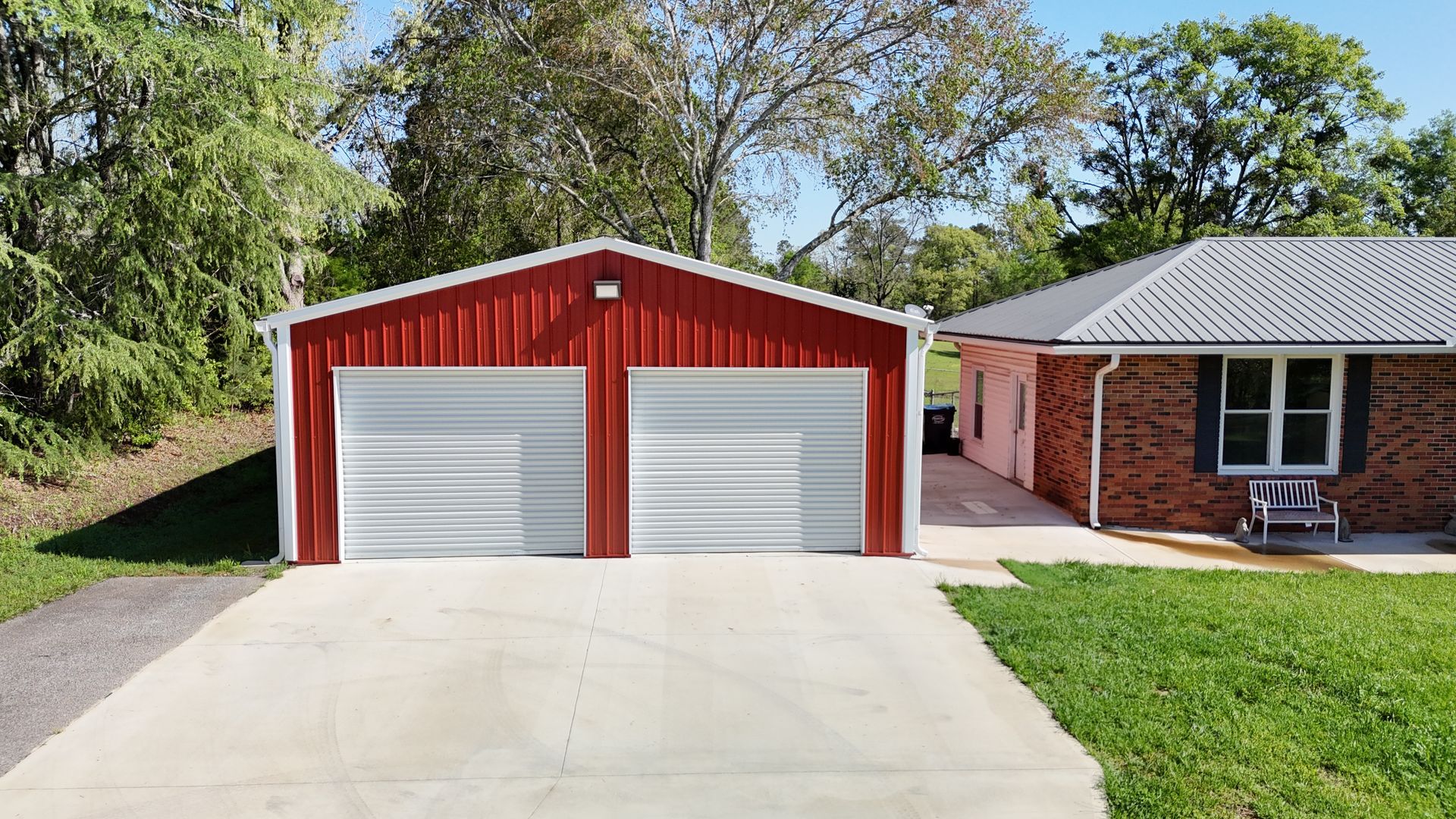 A red garage with two garage doors is next to a brick house.