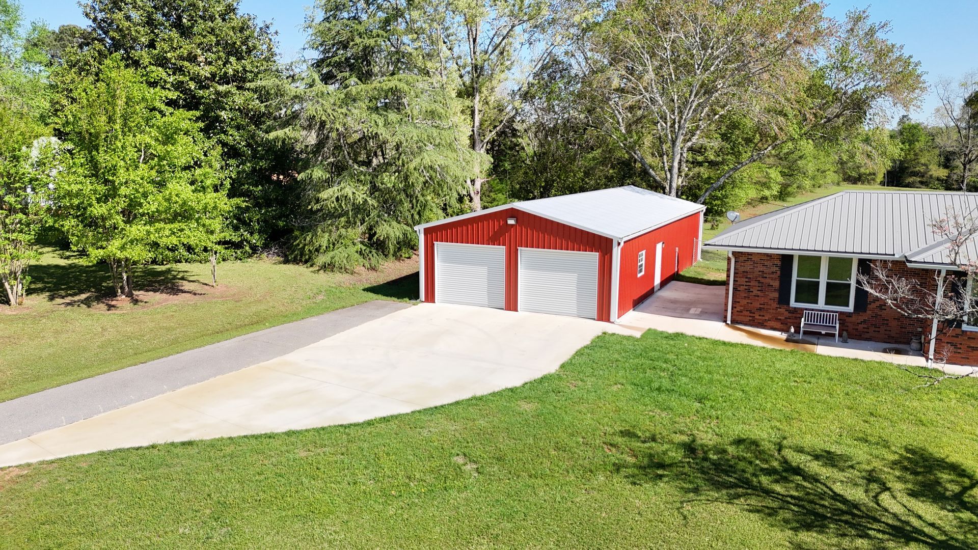 A red garage with two white garage doors is in front of a brick house.