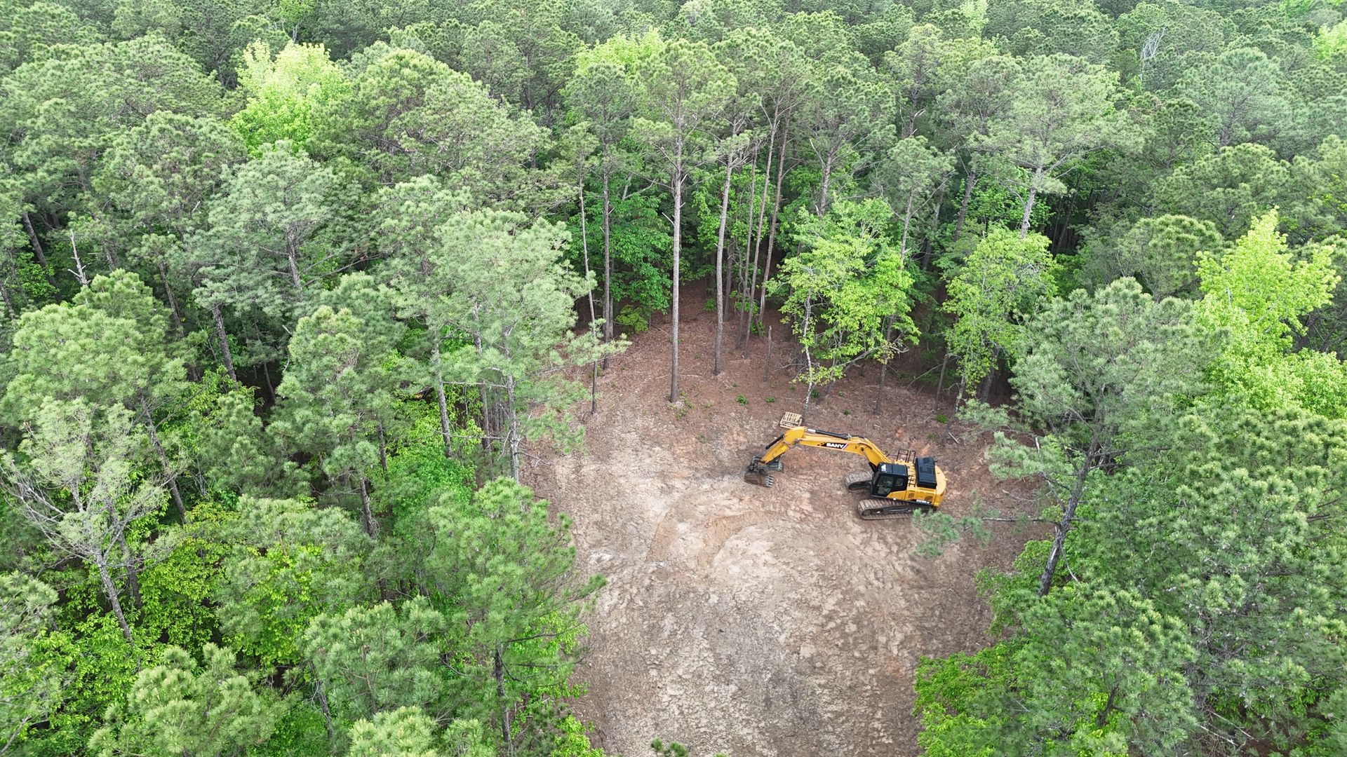 An aerial view of a bulldozer in the middle of a forest.