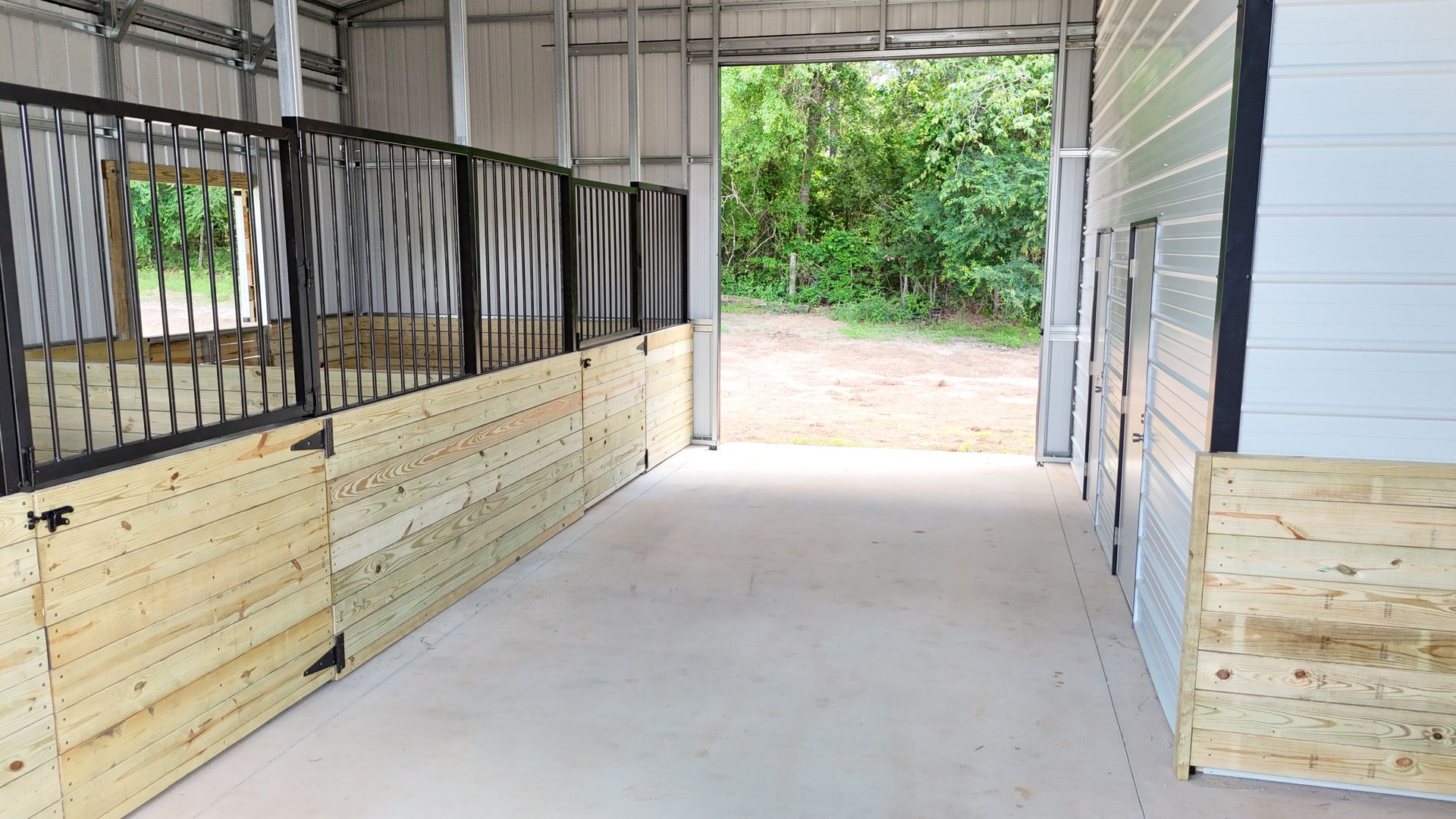 A horse stable with wooden stalls and a concrete floor.