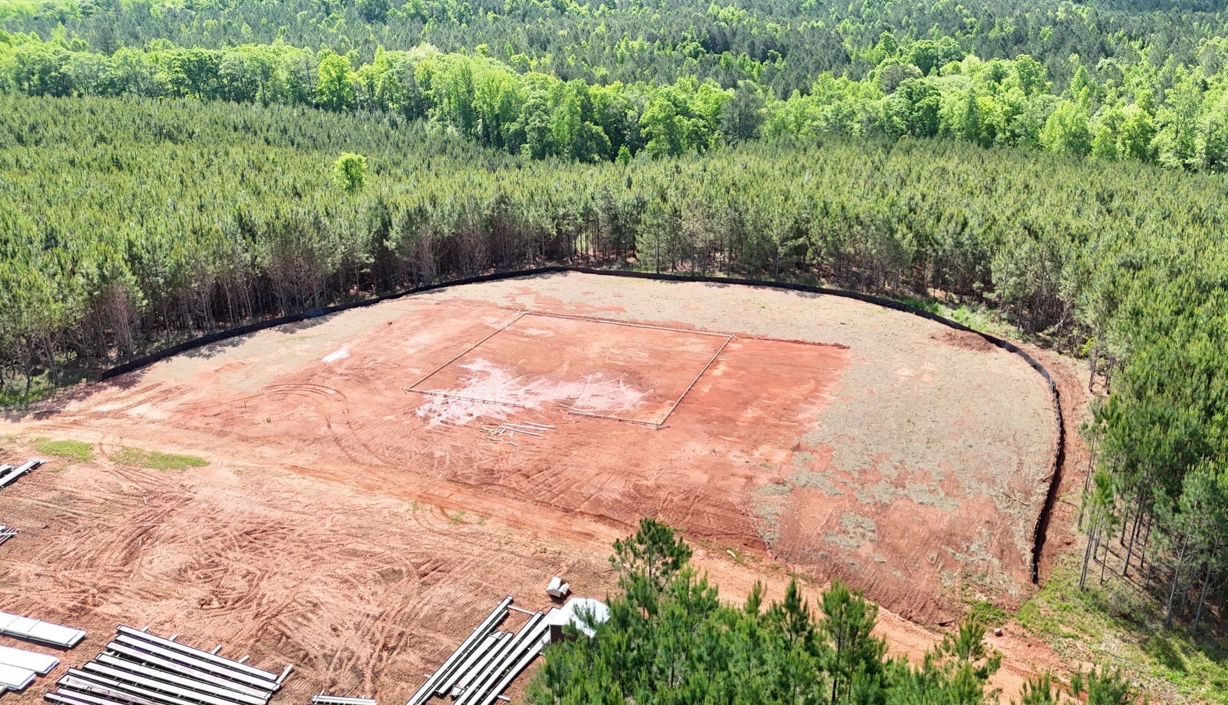 An aerial view of a field in the middle of a forest.