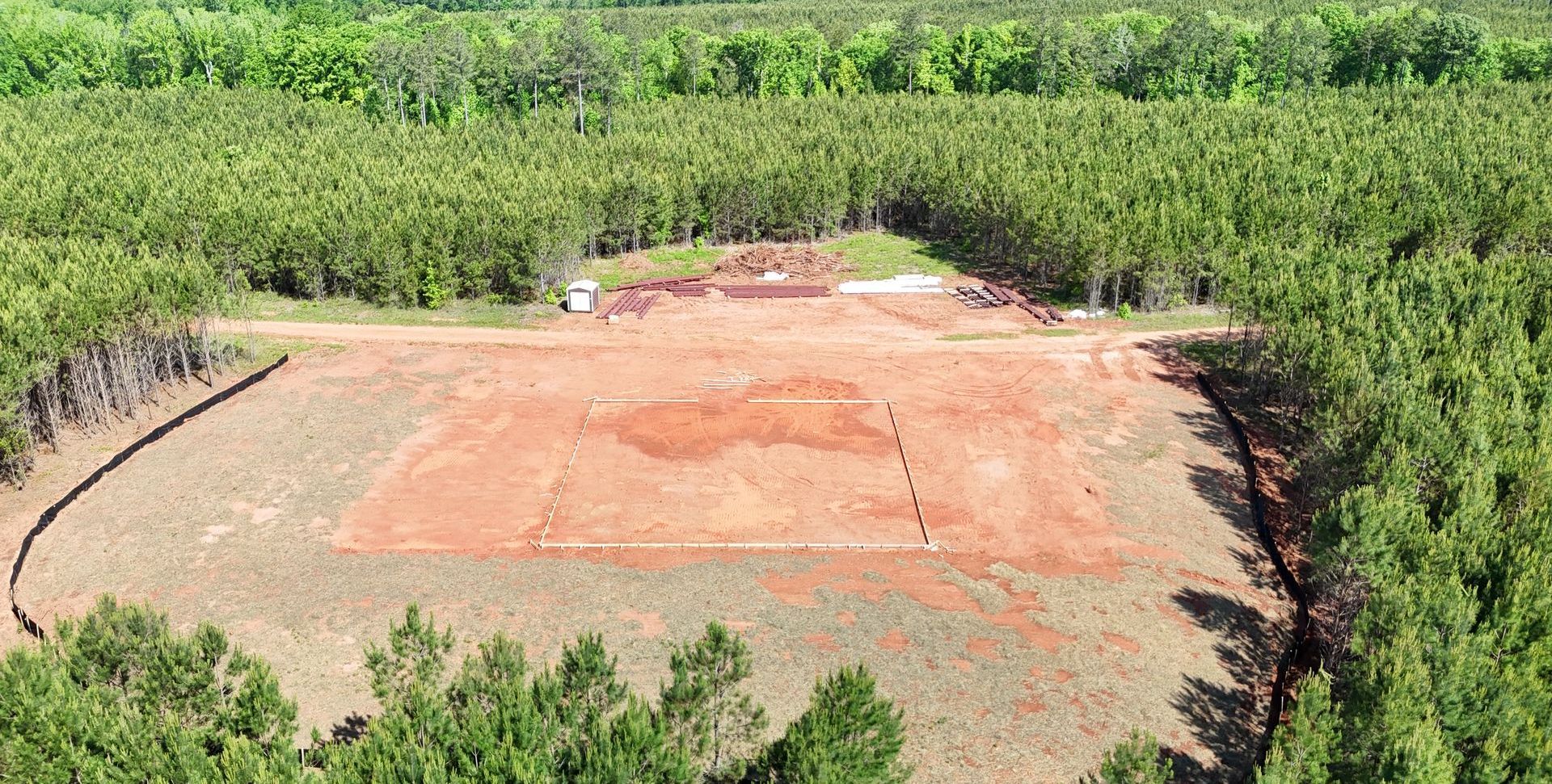An aerial view of a field surrounded by trees and dirt.