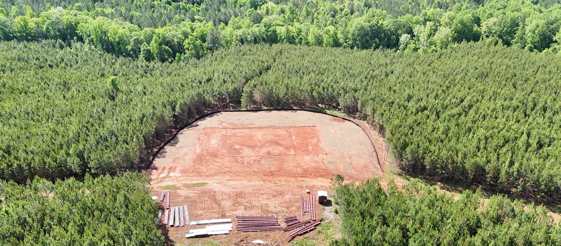 An aerial view of a field surrounded by trees and dirt.