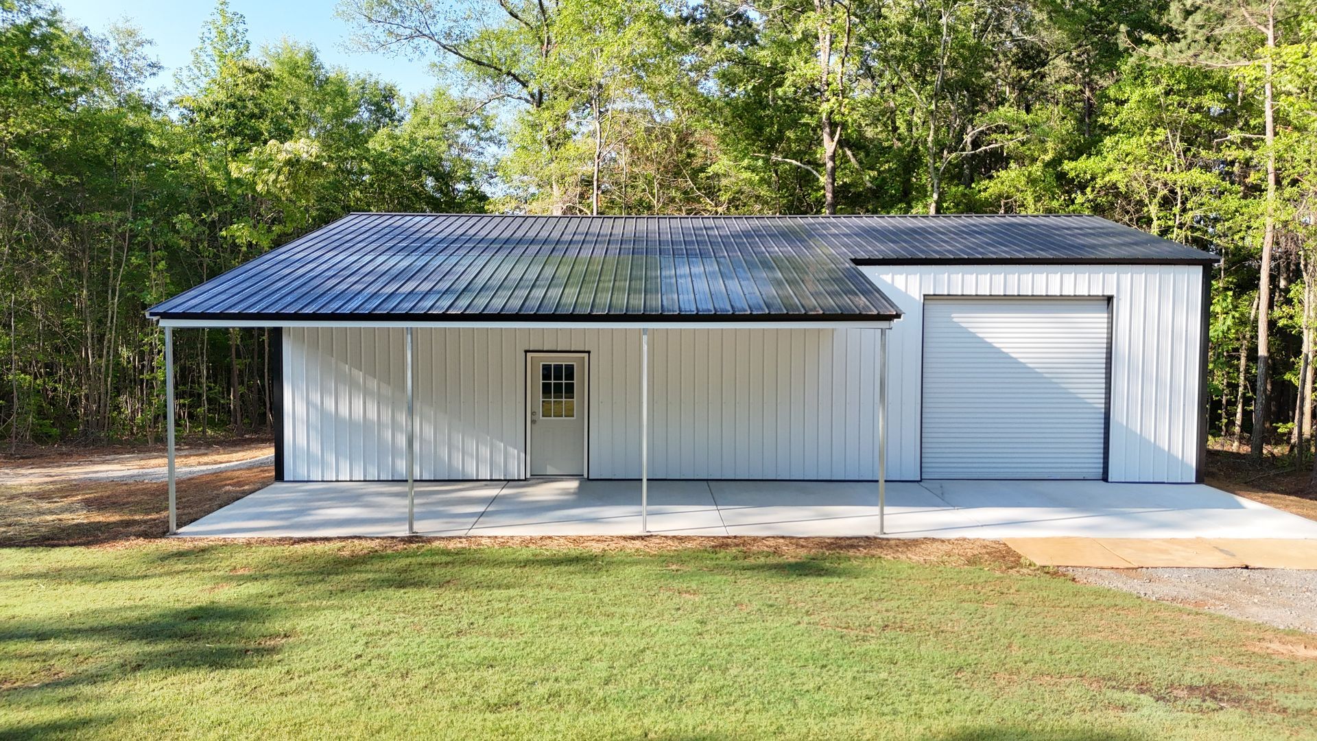 A white garage with a black roof and a porch.