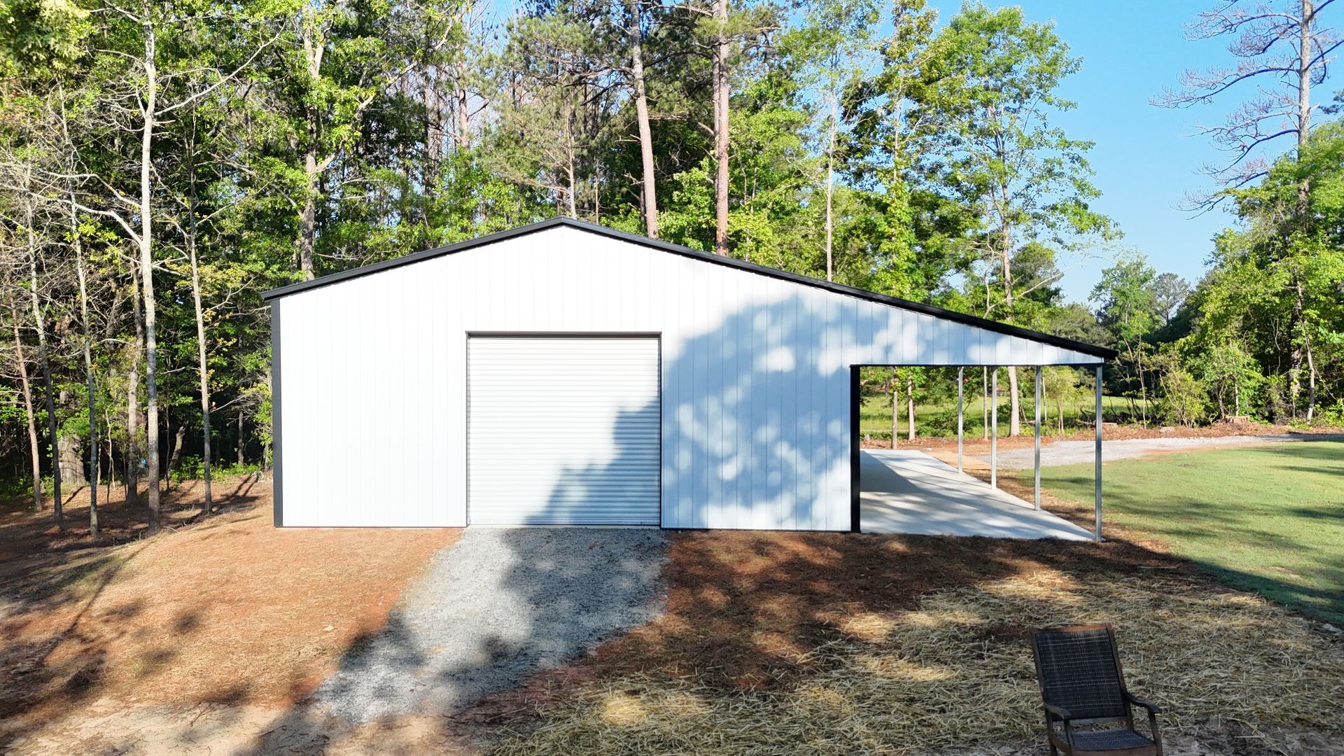 A white garage with a driveway and trees in the background.