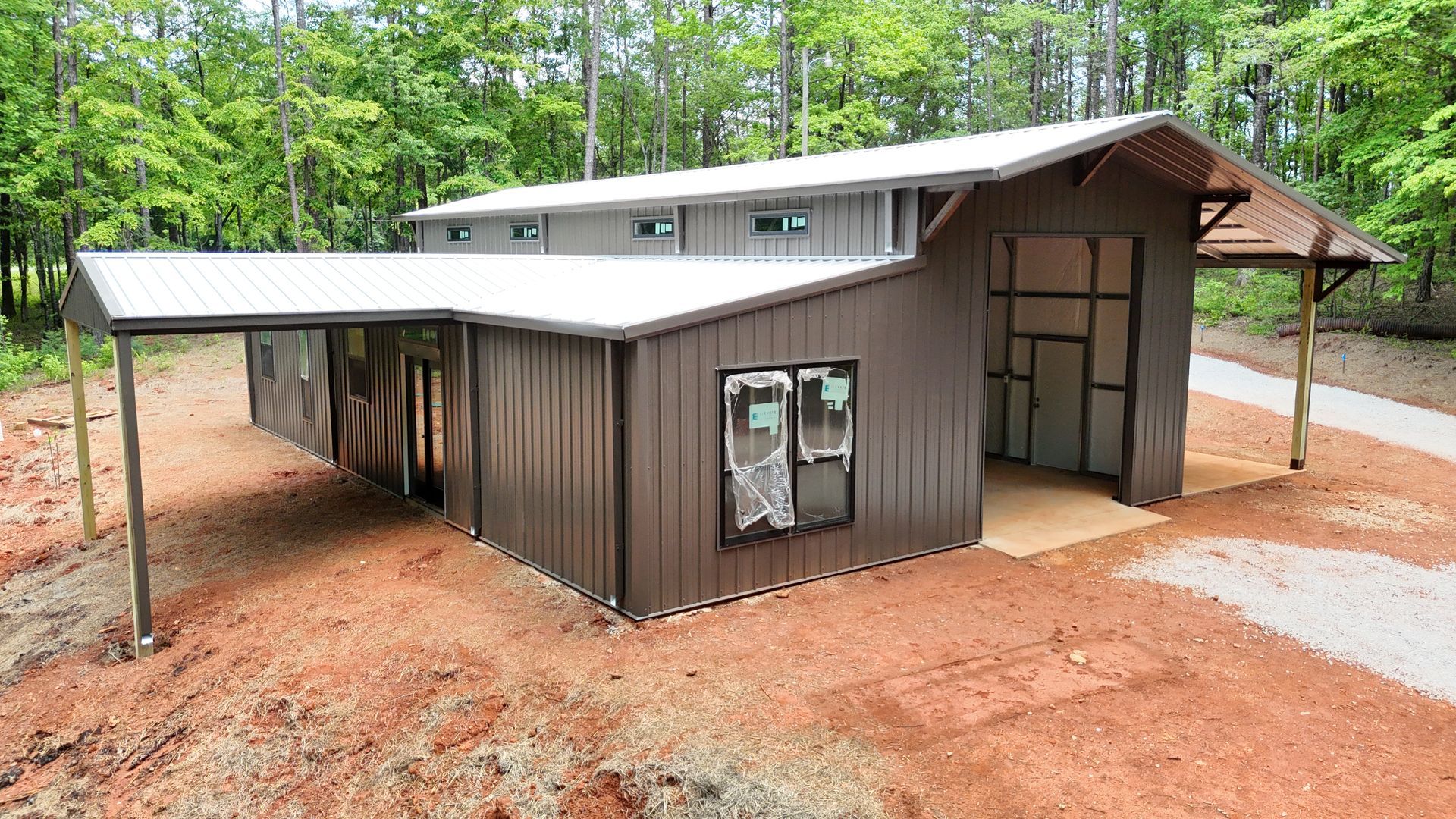 A metal building with a carport attached to it is sitting on top of a dirt hill.