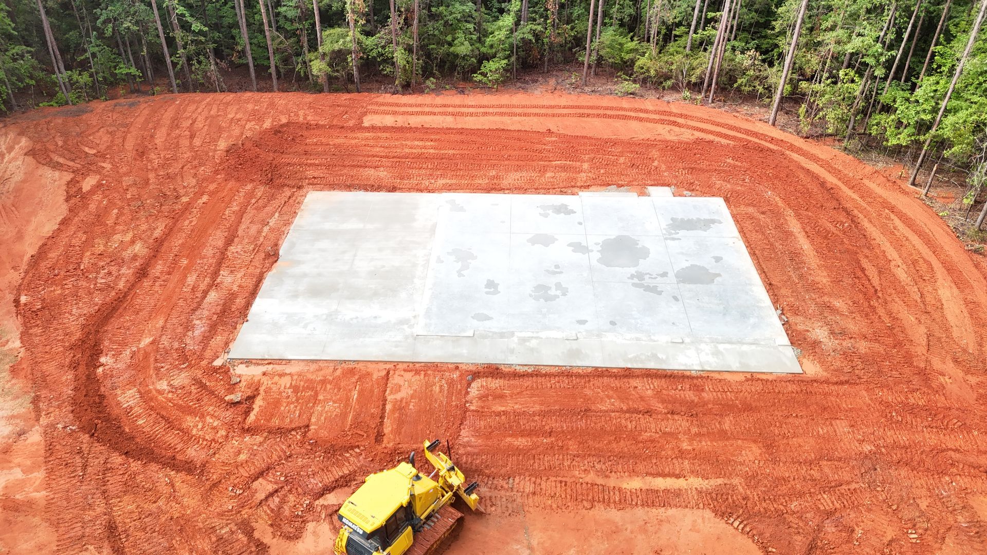 An aerial view of a bulldozer moving dirt in a field.