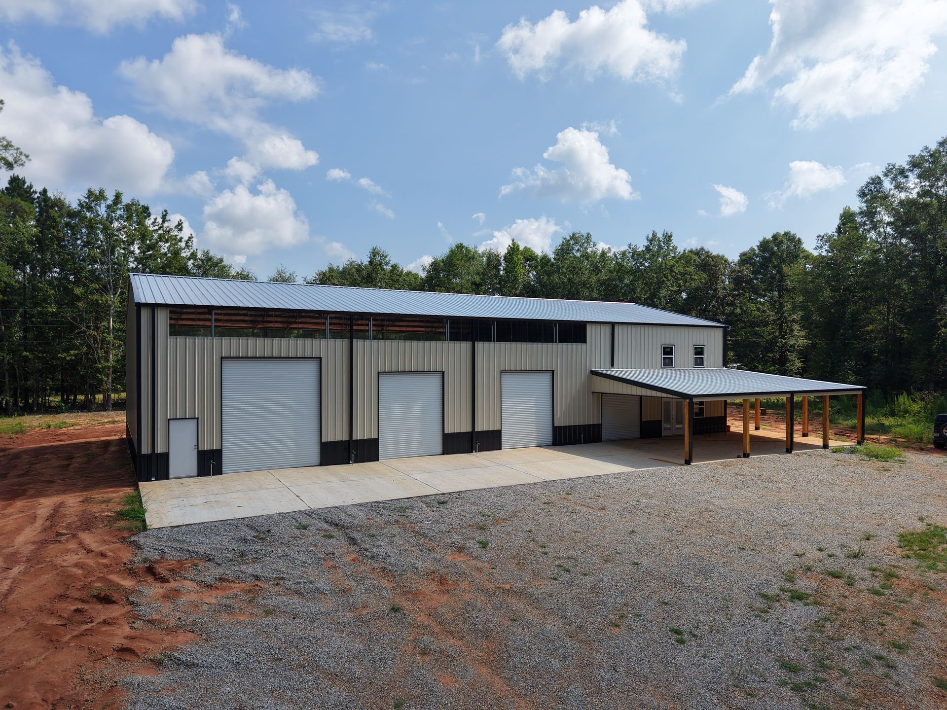 A large metal building with three garage doors and a carport