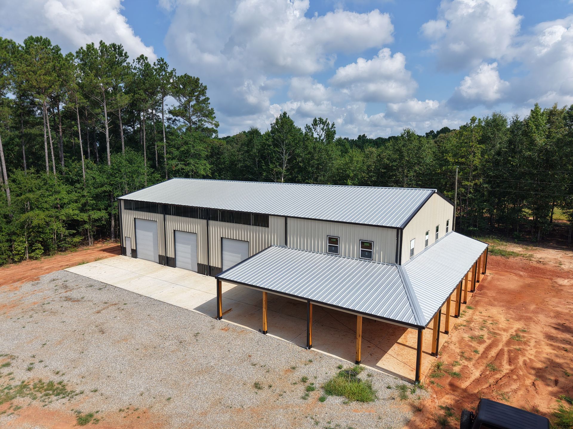 An aerial view of a large metal building in the middle of a forest.