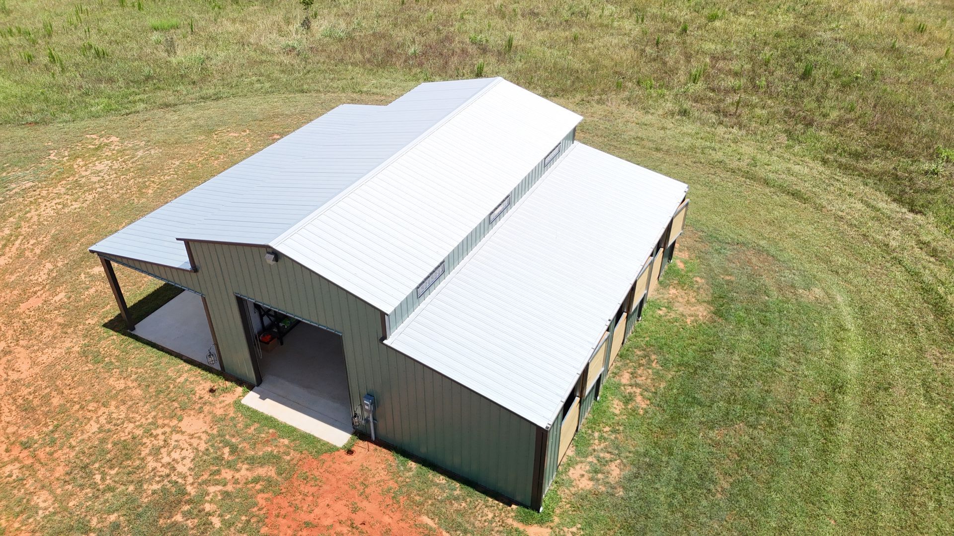 An aerial view of a metal building in the middle of a grassy field.