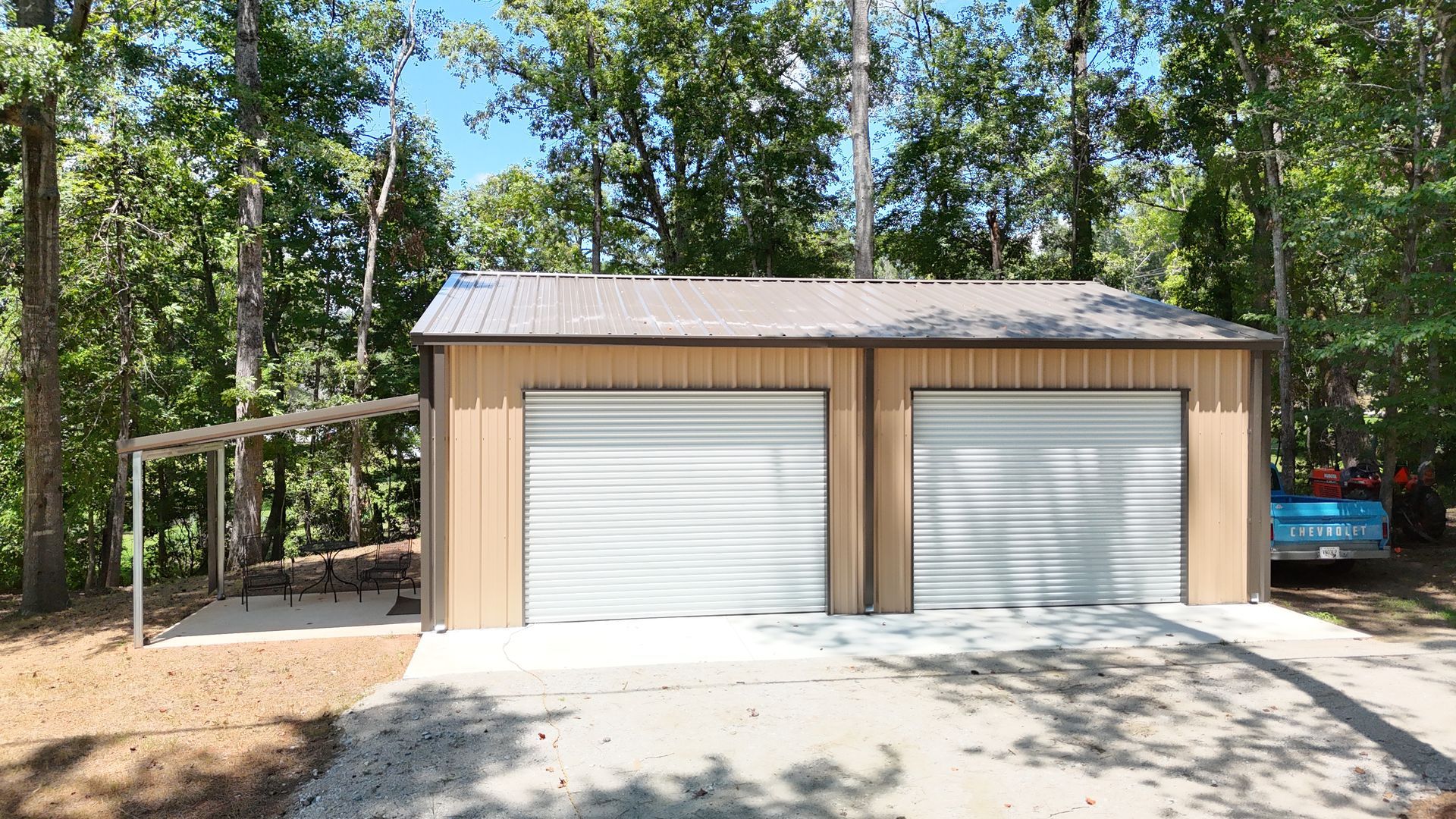A garage with two garage doors is surrounded by trees.