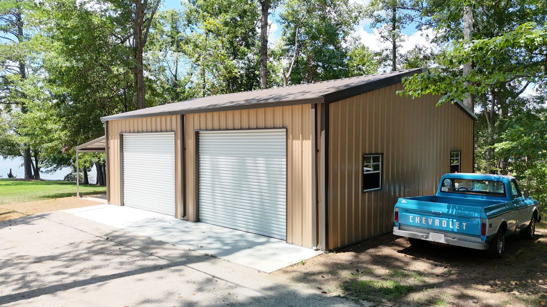 A blue truck is parked in front of a garage.