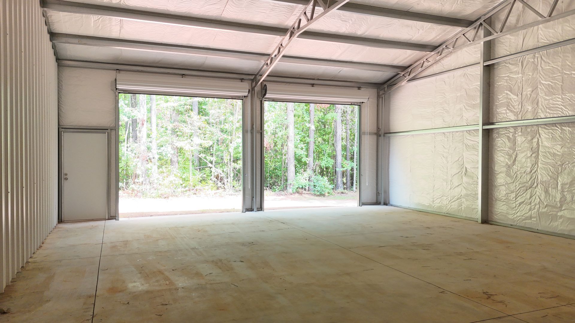 A large empty warehouse with two garage doors open.