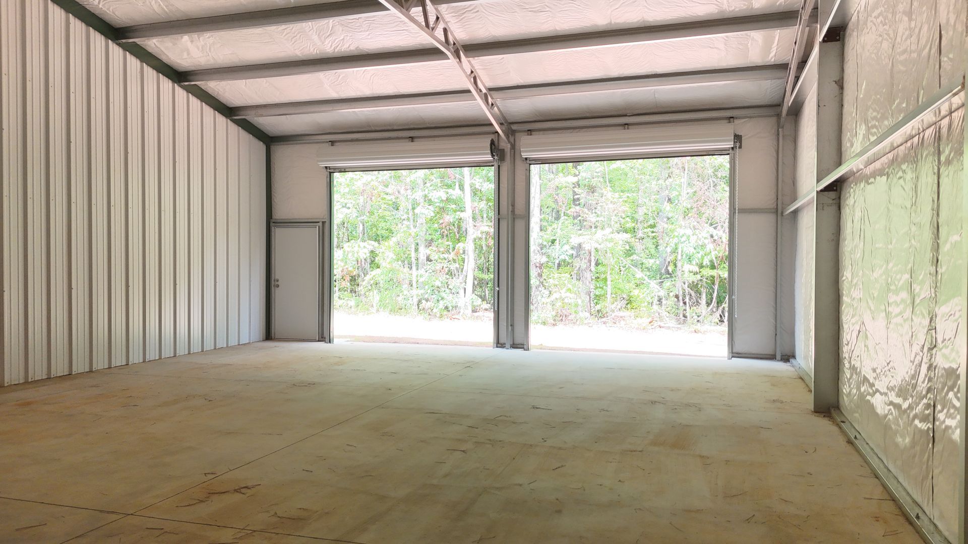 A large empty garage with two garage doors open.