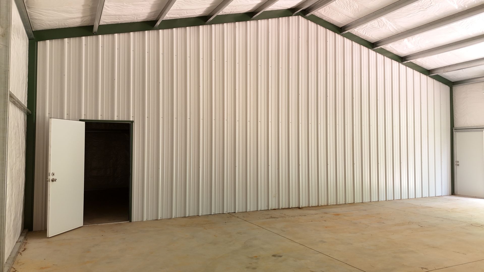 A large empty metal building with a door open.