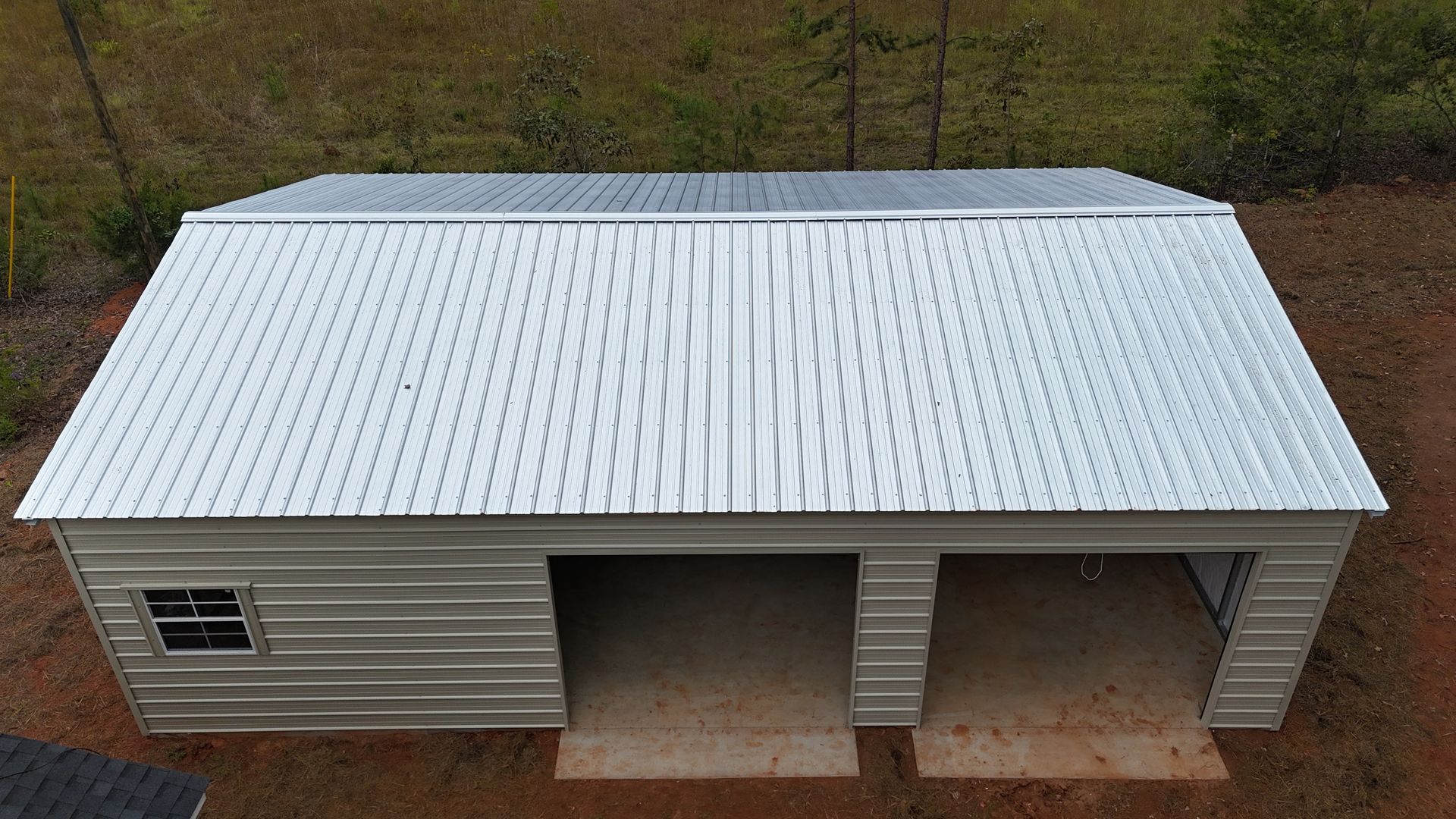 Two-car metal garage with a small window and a white corrugated roof.