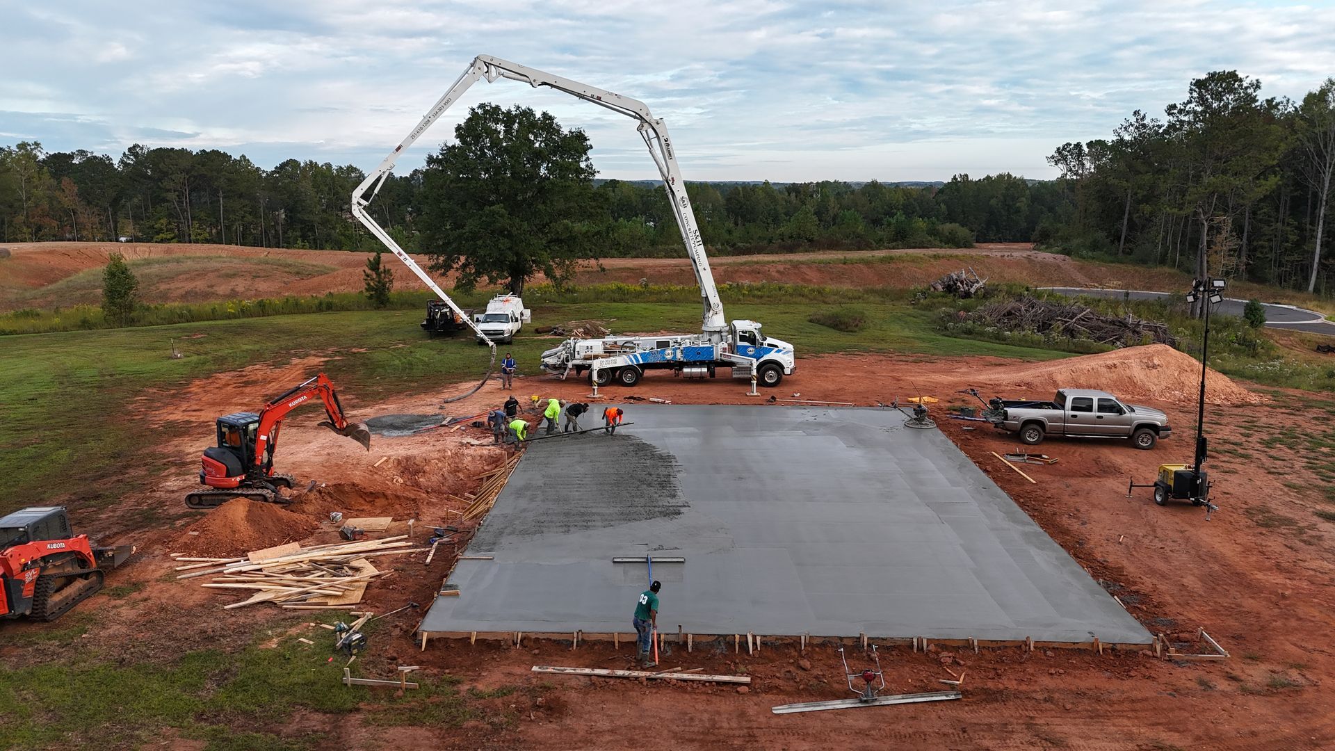 Concrete pouring a foundation on a construction site. A cement truck is pumping concrete. Workers are smoothing it.